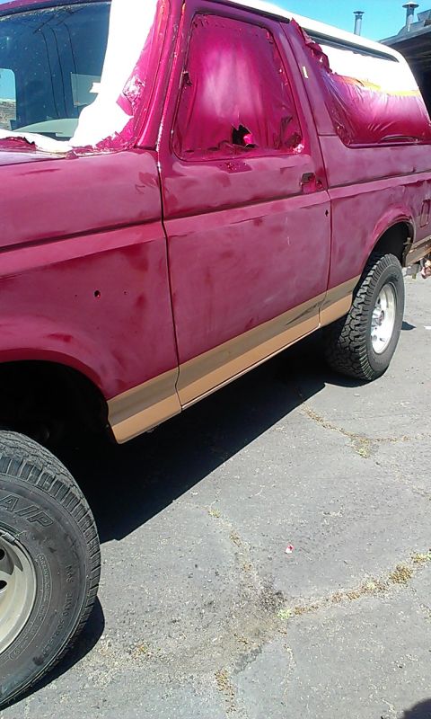 1994 Ford Bronco - Side view of a red Ford Bronco with its windows covered in pink plastic sheeting.