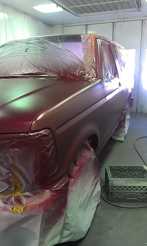 1994 Ford Bronco - An SUV is prepped for painting inside a spray booth, covered in protective sheeting.