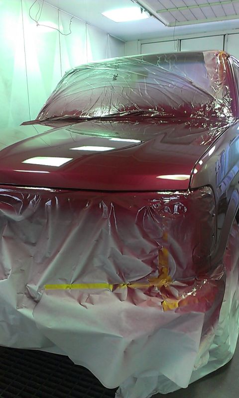 1994 Ford Bronco - A red SUV is being prepped for painting inside a booth, with plastic covering most of its body.