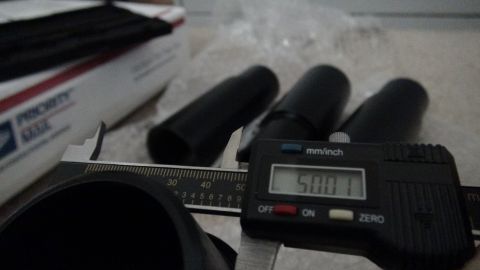 1995 Ford Taurus - Digital caliper measures a black coilover part to 50.01 mm, with other parts and packaging in the background.