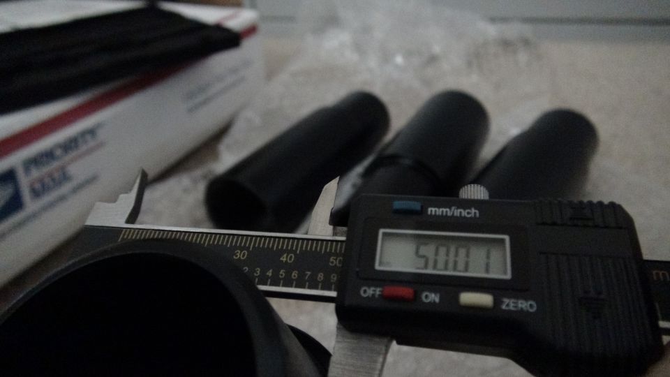 Digital caliper measuring black coilover part, reading 50.01 mm