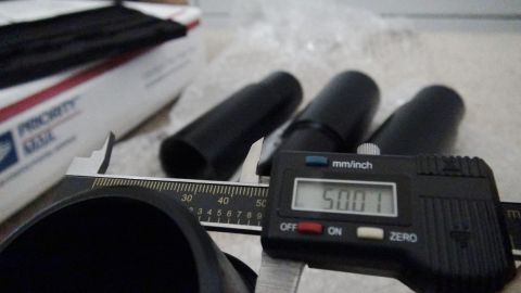 1995 Ford Taurus - Digital caliper measures 50.01mm on black cylindrical parts, next to a Priority Mail box.