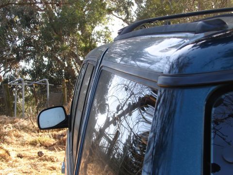1973 Ford Ranchero - The side profile of a dark blue SUV is visible, reflecting trees and sky.