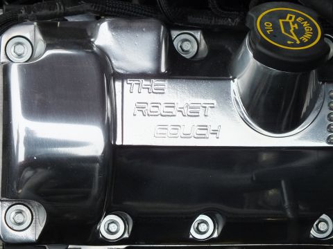 2003 Ford Crown Victoria - Chromed Ford valve cover engraved with the words THE ROCKET COUCH beside a yellow engine-oil filler cap.