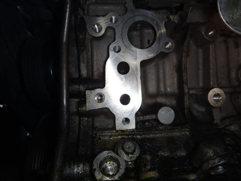 2000 Lincoln Continental - Close-up view of an engine block with a metal component attached.