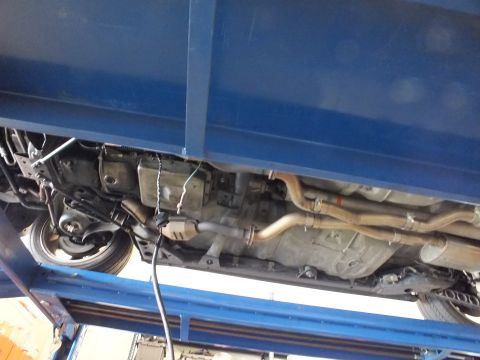 2003 Ford Crown Victoria - Underside view of a vehicle on a blue lift exposing the exhaust pipes, transmission and suspension