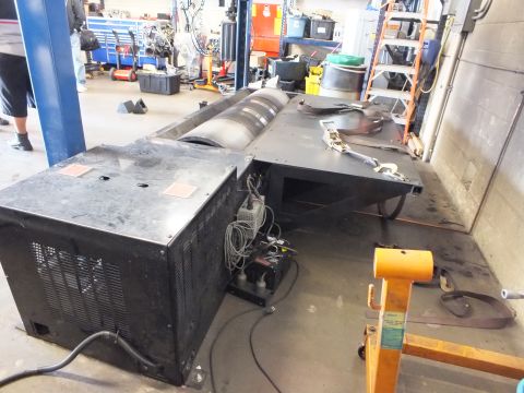 2003 Ford Crown Victoria - Chassis dyno roller assembly on a shop floor next to its control cabinet and connecting cables