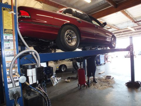 2003 Ford Crown Victoria - Profile of a maroon full-size sedan with rear drag wheels raised on a four-post shop lift