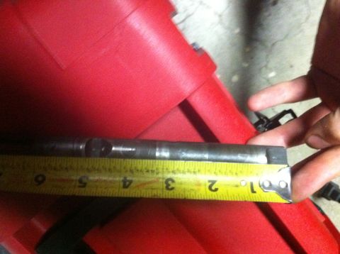 1989 Ford Bronco - A metal shaft is measured against a red plastic housing with a yellow tape measure.