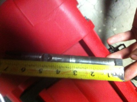 1989 Ford Bronco - A metal rod is measured against a yellow tape measure, with a red plastic object in the background.