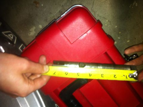 1989 Ford Bronco - A metal rod is being measured with a yellow tape measure against a red toolbox.