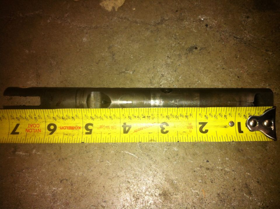 Metal shaft measured against a yellow tape measure, approximately 7 inches long
