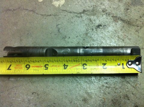 1989 Ford Bronco - A metal shaft is shown with a yellow measuring tape, indicating its dimensions.