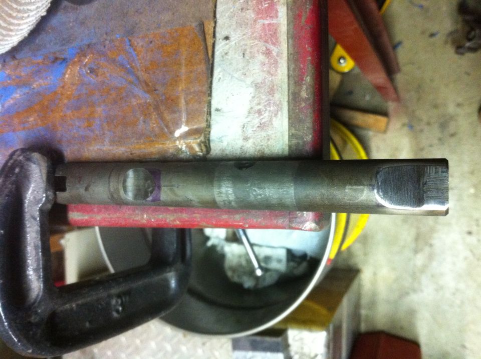 Metal shaft clamped in a vise with a red bar underneath
