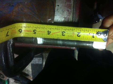 1989 Ford Bronco - A metal rod is being measured with a yellow tape measure while secured in a vise.