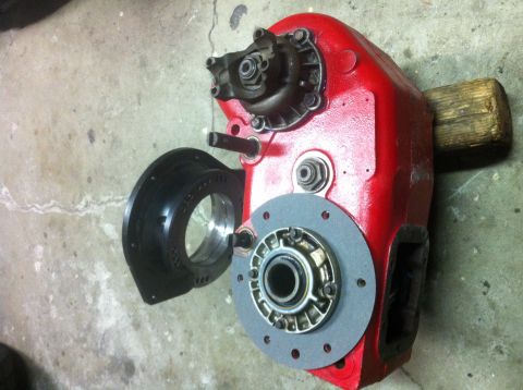 1989 Ford Bronco - A red transfer case housing is shown disassembled with its associated parts on a concrete floor.