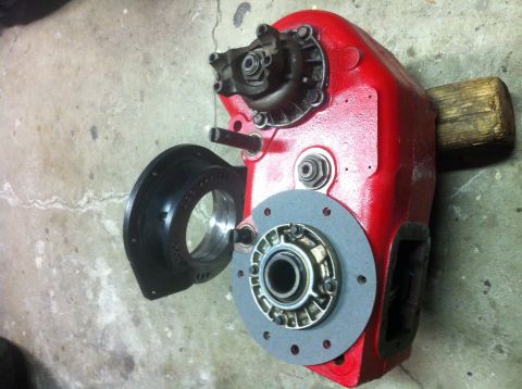 1989 Ford Bronco - A red transfer case part, possibly for a Ford Bronco, is shown disassembled with a black adapter and bearing assembly.