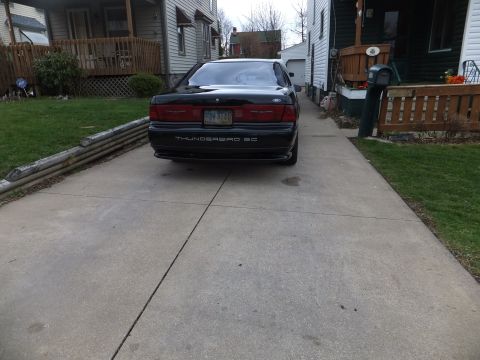 1970 Ford Ranchero - The rear of a black Ford Thunderbird SC is visible in a residential driveway.
