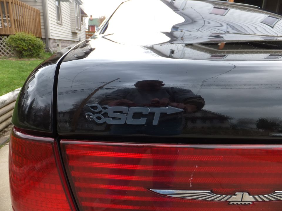 Close-up of a black car's trunk lid with an SCT emblem and part of a taillight