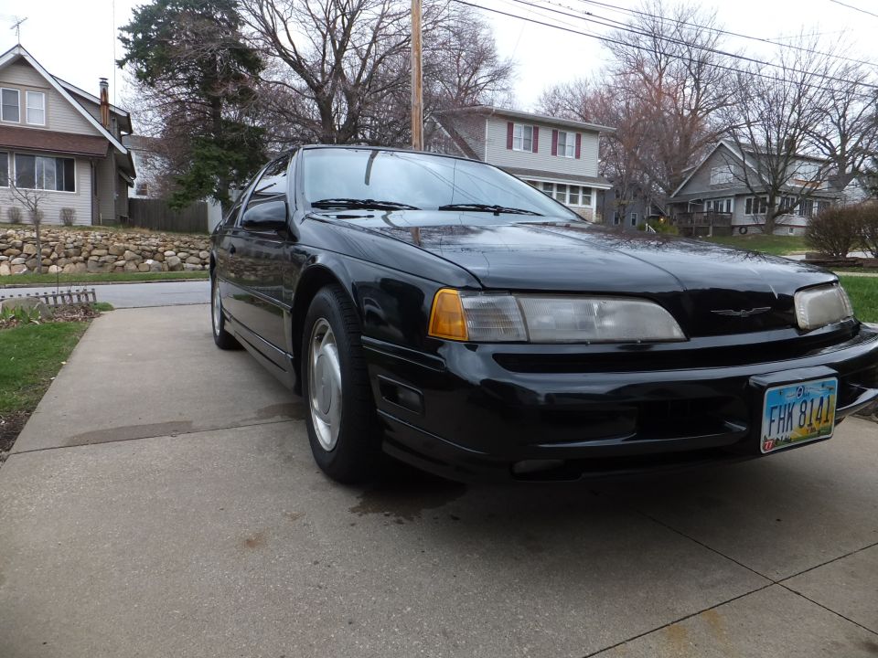Black coupe with a Thunderbird emblem on the grille, front 3/4 view