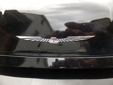 1970 Ford Ranchero - Close-up of a chrome emblem on a black surface, possibly a car part.