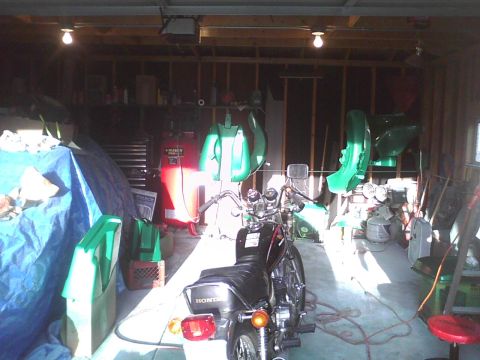 2003 Ford Crown Victoria - A motorcycle is parked inside a cluttered garage with various items hanging on the walls.