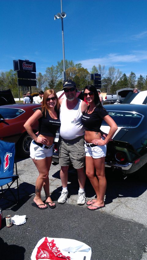 1980 Pontiac Trans Am - A black muscle car with white stripes is parked outdoors with two women posing next to it.