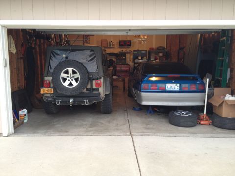 1990 Ford Mustang - A 1990 Ford Mustang and a Jeep Wrangler are parked inside a garage.