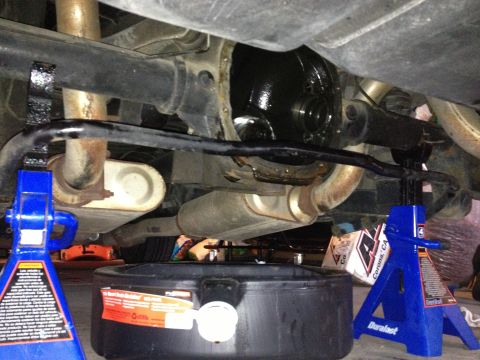 1990 Ford Mustang - Underneath view of a 1990 Ford Mustang's rear differential and exhaust system, supported by jack stands with an oil drain pan below.