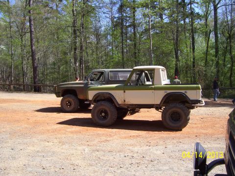 1990 Ford Bronco - A modified Ford Bronco sits parked next to another SUV in a wooded area.