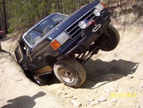 1990 Ford Bronco - Ford Bronco navigating a challenging off-road obstacle, with another vehicle in the background.