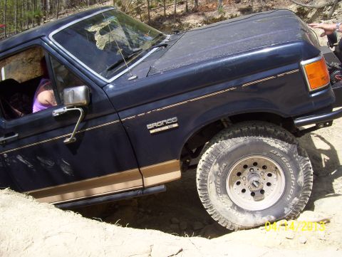 1990 Ford Bronco - This Ford Bronco is navigating a challenging off-road terrain with steep inclines and loose dirt.