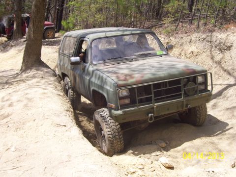 1990 Ford Bronco - This SUV, likely from the 1980s, navigates a challenging off-road course with other vehicles visible in the background.