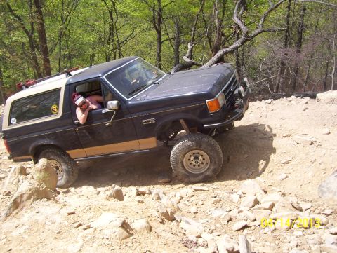 1990 Ford Bronco - A Ford Bronco navigates a challenging off-road trail with steep inclines and rocky terrain.