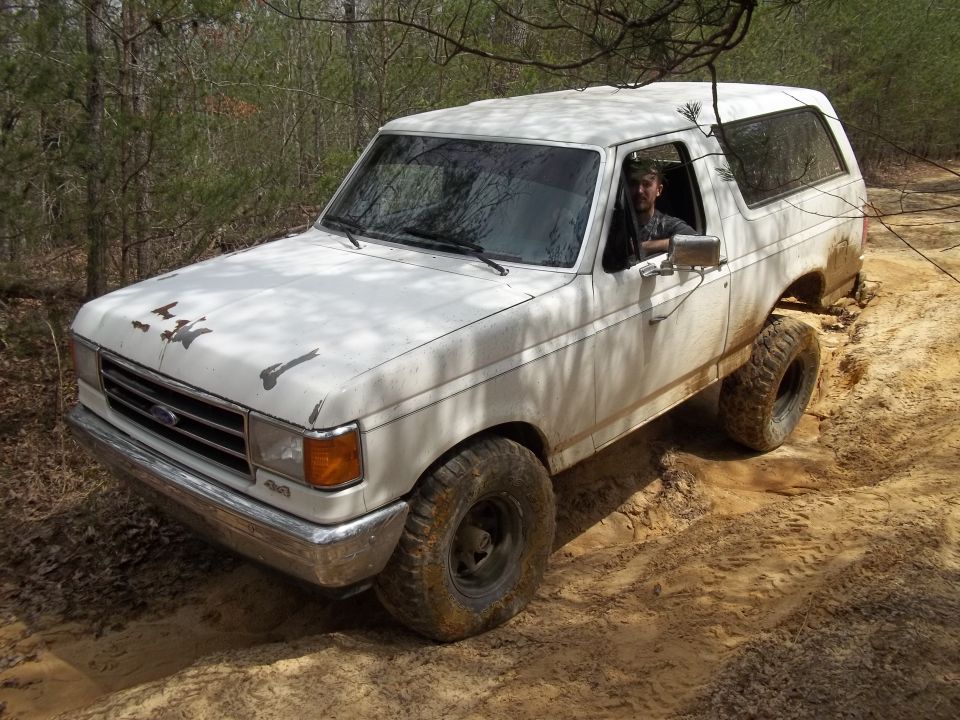 White 1990 Ford Bronco off-roading on a dirt trail