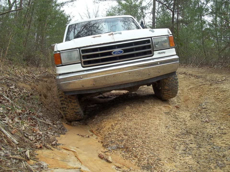 White Ford truck with chrome grille and bumper, driving off-road