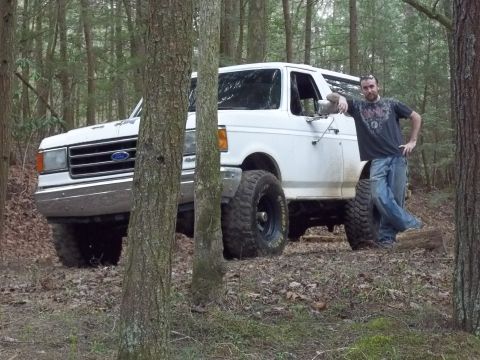 1990 Ford Bronco - Man poses with a white 1990 Ford Bronco in a forest setting.