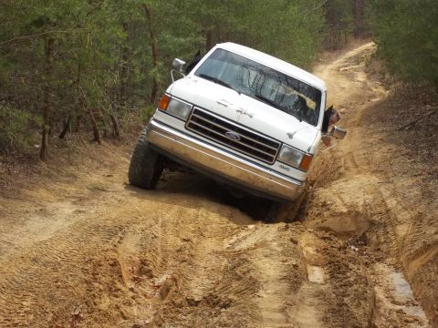 1990 Ford Bronco - This 1990 Ford Bronco tackles a challenging muddy incline on an off-road trail.