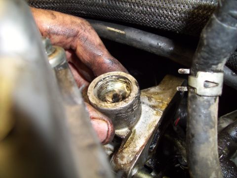 1995 Ford Probe - Close-up of a greasy engine component being worked on, with hoses and wiring in the background.