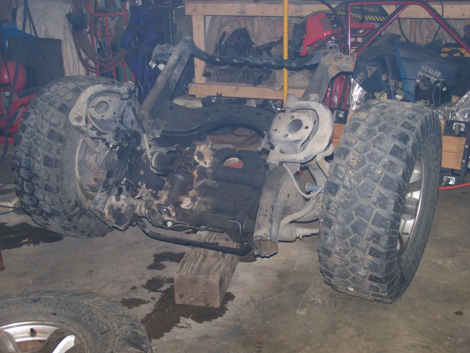 Suzuki Samurai chassis with engine and suspension components, tires mounted