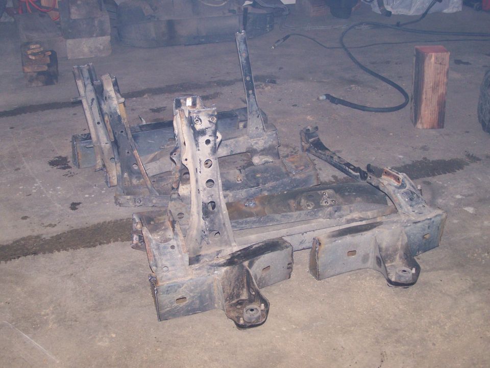 Two disassembled metal vehicle frame sections on concrete floor