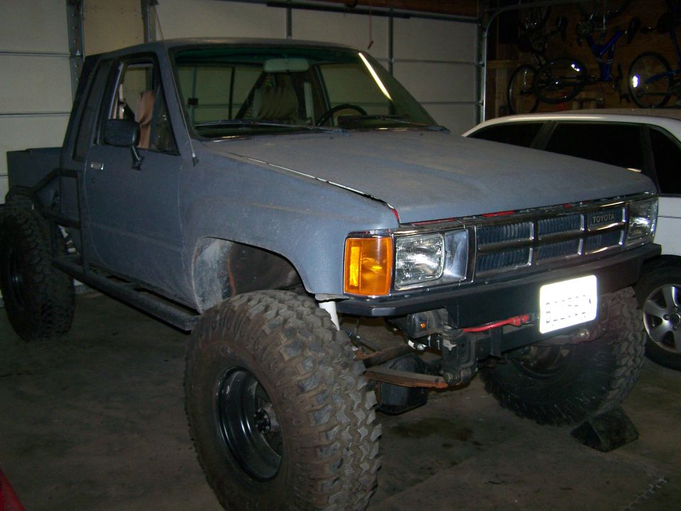 Modified Toyota pickup truck with large tires and roll cage, front view