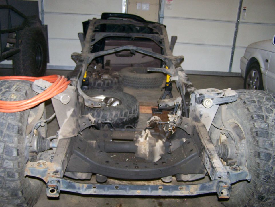 1988 Suzuki Samurai chassis with large tires and orange cables, viewed from the front