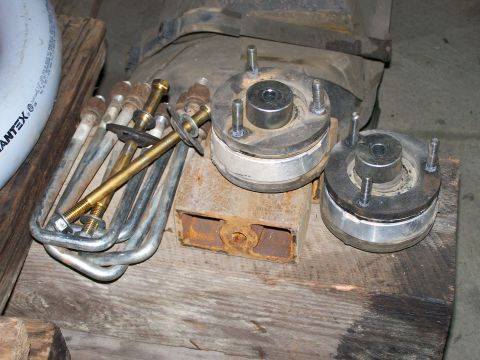 1988 Suzuki Samurai - Several suspension components, including U-bolts and shock mounts, are laid out on a wooden surface.