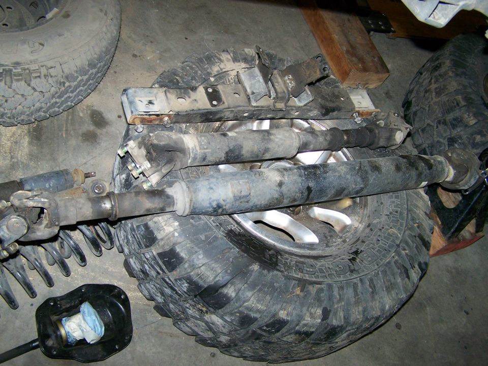 Driveshafts and tires on a garage floor. A black transfer case boot is visible