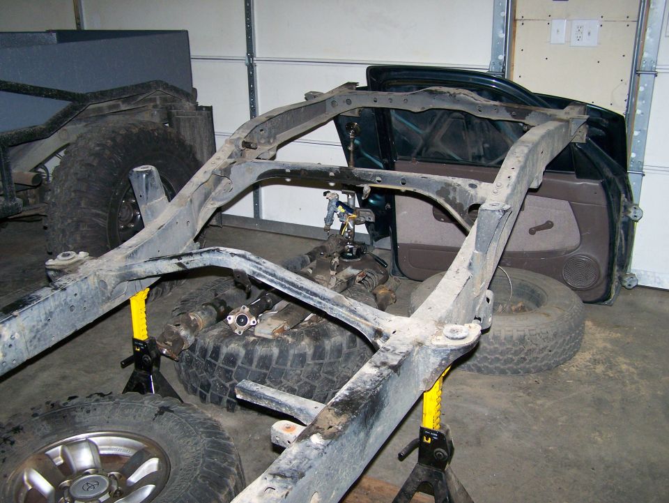 Vehicle frame on jack stands with spare tires and doors