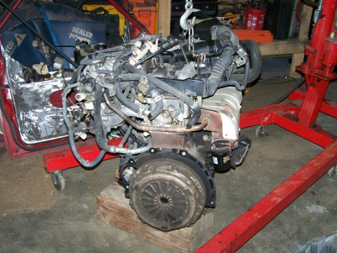 1988 Suzuki Samurai - Engine assembly removed from a vehicle and mounted on a red engine stand for service.