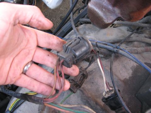 1981 Ford Bronco - A hand is shown disconnecting an electrical connector from a vehicle's engine bay wiring.