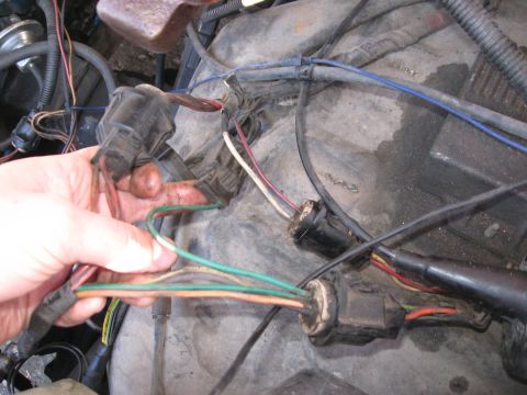 1981 Ford Bronco - Close-up of a hand manipulating wires within an engine bay, likely for repair or diagnosis.