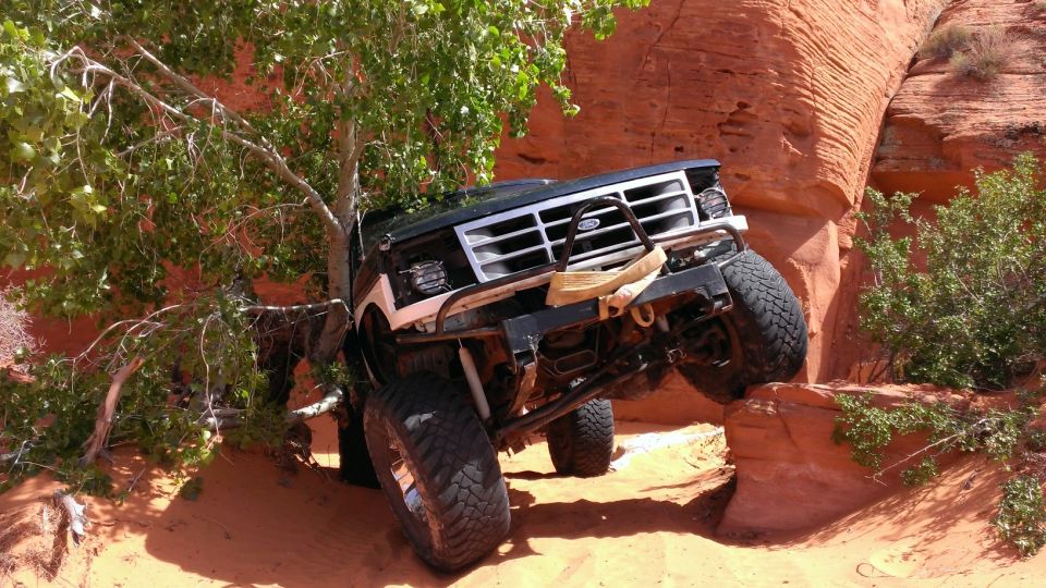 Black Ford Bronco with off-road modifications climbing red rocks